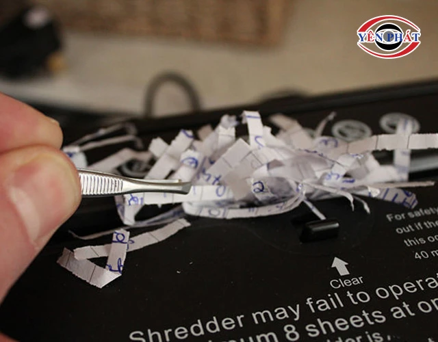 Dùng nhíp kéo giấy kẹt khỏi lưỡi dao